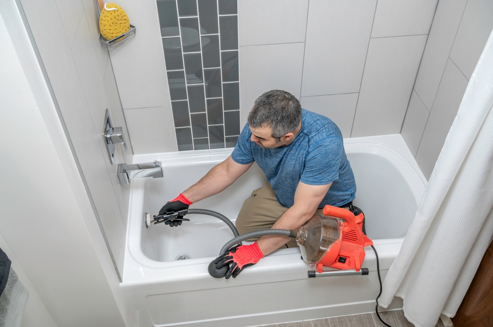 An image of a professional plumber using specialized equipment to clear clogs from a drain system. The image represents the importance of professional drain cleaning for maintaining a healthy and functioning plumbing system in a Germantown home.